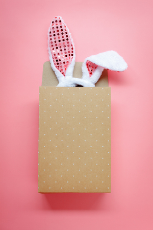 Table top view aerial image of decoration & symbol Happy Easter holiday background concept.Flat lay accessory costume bunny ear with paper bag on modern beautiful pink paper at home office desk.の写真素材