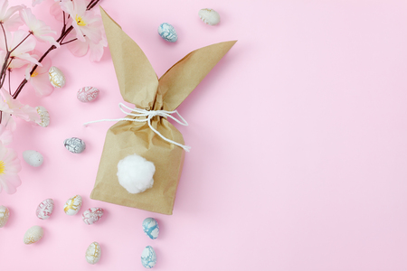 Top view shot of arrangement decoration Happy Easter holiday background concept.Flat lay colorful paper bag rabbit ear for gift with eggs and blossom on modern pink paper at office desk.pastel tone.の写真素材
