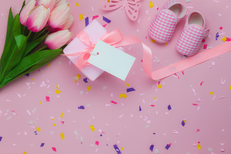 Table top view aerial image of decoration Happy Mothers day holiday background concept.Flat lay gift box & tulip flower with  kids shoe on beautiful pink paper.Pastel tone creative design mock up.の写真素材