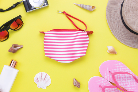 Table top view aerial image of items to travel summer holiday background concept.Flat lay essentials accessories for travel to beach trip.Fashion pink hand bag with women clothing on yellow paper.の写真素材