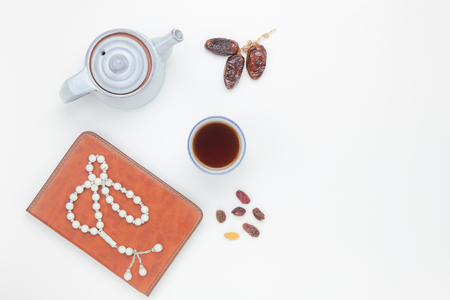 Table top view aerial image of decoration Ramadan Kareem holiday background.Flat lay dates with white rosary & cup tea.The holy book of Koran on modern white wood at office desk.Free space design.の写真素材