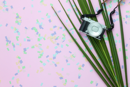 Table top view aerial image of items to travel summer holiday background concept.Flat lay sign of season for travel to beach trip.Camera with green coconut leaf on confetti pink paper with copy space.の写真素材