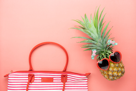 Table top view aerial image of summer & travel beach holiday in the season background concept.Flat lay sign objects on season for travel.Hand bag pineapple wear sunglasses on pink paper.Free space.の写真素材