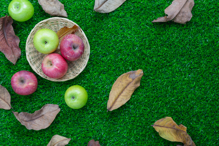 Table top view aerial image of decoration Fall harvest or Rosh Hashanah day background concept.Flat lay apple in basket with dry leaf all objects on modern rustic green grass.Copy space for add text.の写真素材