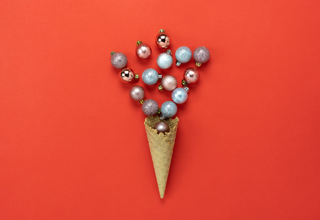 Table top view of Merry Christmas decorations & Happy new year ornaments concept.Flat lay essential difference objects baubles & ice cream cone laying on modern red paper background at office desk.の写真素材