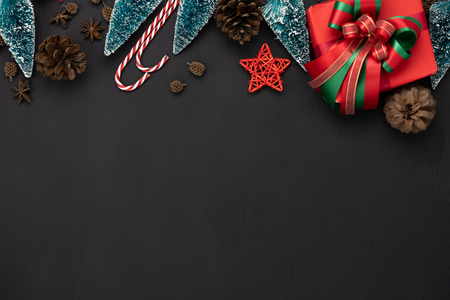 Table top view of Merry Christmas decorations & Happy new year ornaments concept.Flat lay essential objects the fir tree & gift box on modern rustic black wood background at home studio office desk.の写真素材