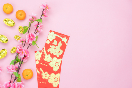 Chinese language mean rich or wealthy and happy.Table top view Lunar New Year & Chinese New Year concept background.Flat lay object the orange & red pocket money with gold decoration on pink paper.の写真素材