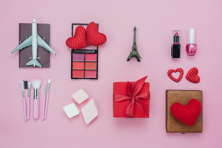 Table top view aerial image of decoration valentine's day background concept.Flat lay essential items red heart & gift box on modern pink paper with clothing women & cosmetic for travel Paris France.の写真素材