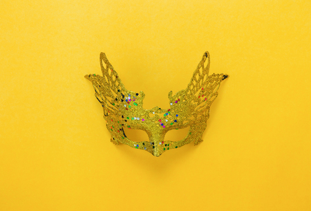Table top view aerial image of beautiful colorful carnival season or photo booth prop Mardi Gras background.Flat lay object gold mask on modern yellow wallpaper.Free space for creative design mockの写真素材