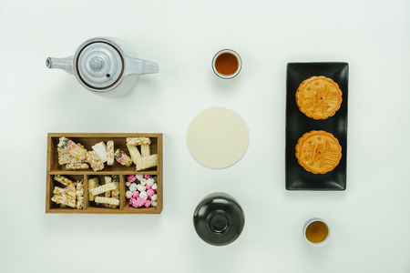 Table top view aerial image Lunar New Year & Chinese New Year concept background.Flat lay essential foot & drink meal set the sweet dessert & cup of tea with moon cake on modern rustic white paper.の写真素材