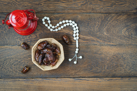 Table top view aerial image of decoration Ramadan Kareem holiday background.Flat lay date in wood basket with white rosary & red lantern.Halal meal set for fasting is obligatory for Muslim on wooden.の写真素材