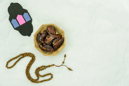 Table top view aerial image of decoration Ramadan Kareem holiday background.Flat lay essential objects dates with rosary & DIY lighting paper on modern rustic white clothing at office desk.copy spaceの写真素材