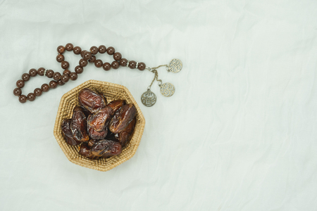 Table top view aerial image of decoration Ramadan Kareem holiday background.Flat lay dates with rosary.Essential object on modern rustic white clothing at office desk.copy space for text design.の写真素材