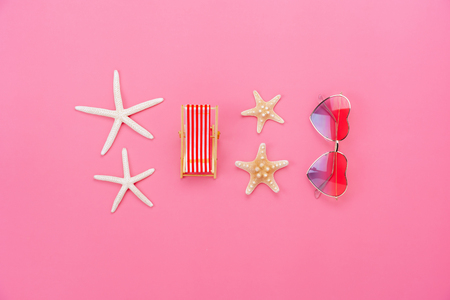 Flat lay image of essential accessories in summer holiday background concept.Sun glasses & Beach table with starfish in vacation season.Table top view several objects sign on pink paper wallpaper.の写真素材