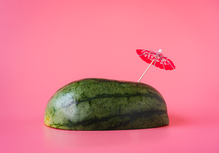 Fruit tropical with spring summer holiday & vacation background concept.Arrangement sliced watermelon & umbrella beach on modern pink paper.Minimal style with pastel tone.Copy space for text & word.の写真素材