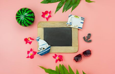 Table top view accessory plan to travel beach in summer holiday background concept.Flat lay  palm leaf with many essential items flower & palm leaf on pink paper.Blackboard for creative design text.の写真素材