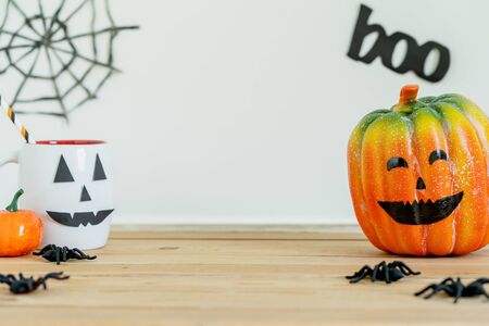 Accessories of decorations Happy Halloween day background concept.Jack O lantern of Cup of drink with pumpkin objects to party season with spider on brown & stone backdrop at home office desk studio.の写真素材