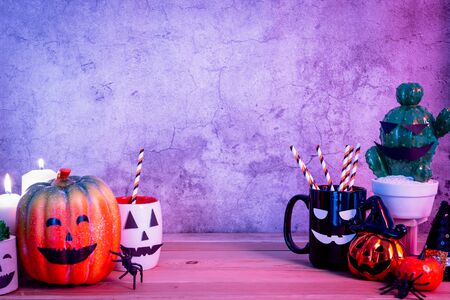 Accessories of decorations Happy Halloween day background concept.Jack O lantern of Cup of drink with pumpkin objects to party season with spider on brown & stone backdrop at home office desk studio.