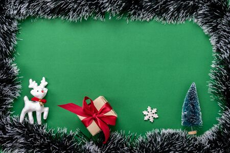 Table top view of Merry Christmas decorations & Happy new year ornaments concept.Flat lay essential difference objects gift box & fir tree on modern green paper background at home studio office desk.の写真素材