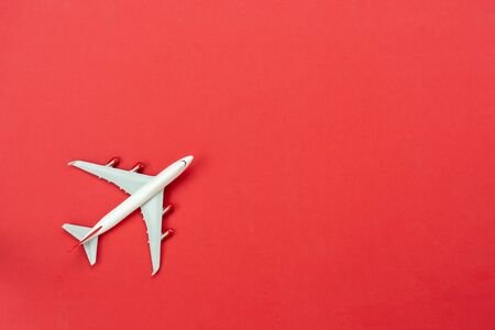 Table top view accessory of accessory travel in holiday background concept.Flat lay of white airplane on modern rustic red paper at home studio office desk.copy space for creative design text.の写真素材