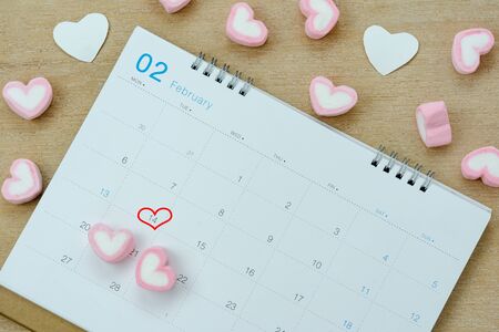 Table top view aerial image of decoration valentine's day background concept.Flat lay arrangement of calendar page of february month with essential items love heart on brown wooden for season.の写真素材