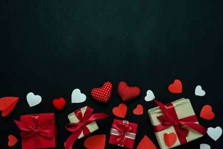 Table top view image of decoration valentine's day background concept.Flat lay arrangement of red shape & gift box with essential items on modern rustic black wood with middle space for mock up designの写真素材