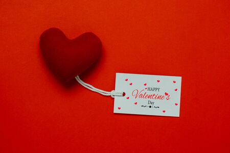 Table top view aerial image of decoration valentine's day background concept.Flat lay arrangement of word season tag & essential items love heart on modern rustic red paper for mock up creative designの写真素材