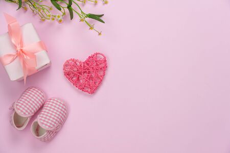 Top view aerial image of decoration Happy mothers day holiday background concept.Flat lay gift box with baby shoes and love shape flower on modern beautiful pink paper at home office desk.copy space.の写真素材
