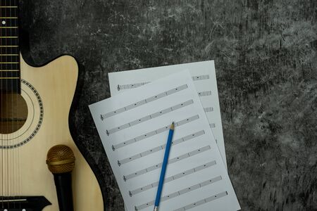Table top view of music instrument tools concept background.Flat lay of sign to sing for musician or party equipment.Paper note and guitar with microphone on modern grey cement.space for design.の写真素材