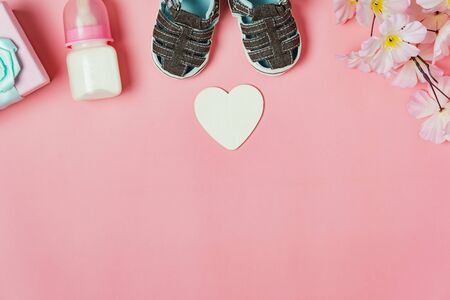 Top view aerial image of decoration Happy mothers day holiday background concept.Flat lay gift box with baby shoes and love shape flower on modern beautiful pink paper at home office desk.copy space.の写真素材