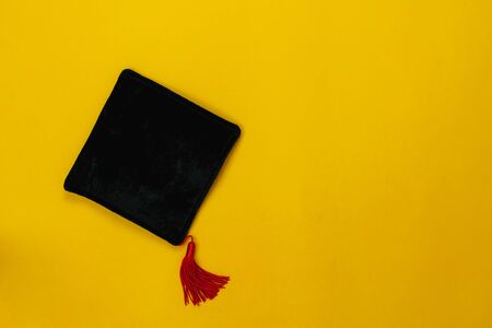 Table top view aerial image of Graduation of education season background concept.Flat lay accessories graduate cap on modern rustic yellow paper.Copy space for creative design mock up.の写真素材