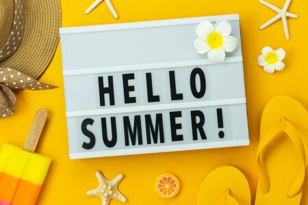 Table top view accessory of clothing women  plan to travel in Hello text summer holiday background concept.Ice cream with many essential items hat & sandals flower, starfish on yellow paper.の写真素材