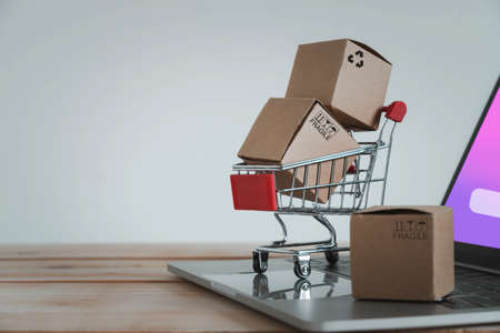 Close up Paper cartons with a shopping cart or trolley on a laptop. Ideas about customers order buy from retailer sites via the internet website.Online shopping,ecommerce and delivery service conceptの写真素材