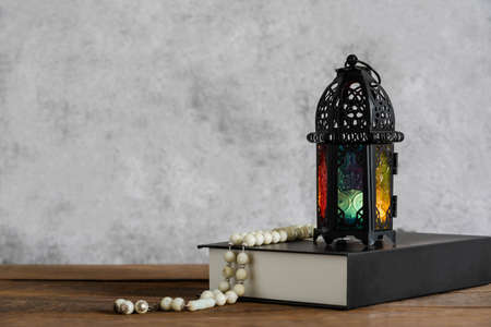 On table top image of decorations Ramadan Kareem holiday background.Close up Arabic lantern metal on brown wooden with Holy Koran and rosary.Set for fasting is obligatory for Muslim on black wooden.の写真素材