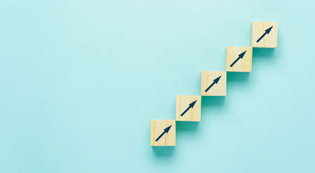 Top view arrow go up on wood block stacking same as step stair on  blue paper background, Business growth up concept. copy space for text. Abstract Success stock market . management achievement.の写真素材