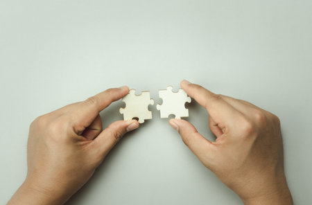 Top view of hand businessman  holding blank puzzle jigsaw pieces. Teamwork success and strategy...