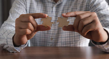 Close up hand businessman  holding blank puzzle jigsaw pieces. Teamwork success and strategy...