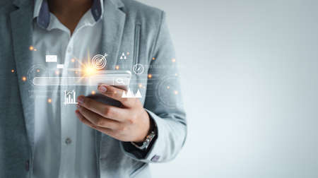 Human using mobile phone technology for digital marketing of darts aiming at the target. business management  goal strategy and action plan. Global customer network connection  on virtual interface.の写真素材
