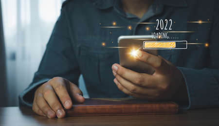 Loading new year 2022.Human using mobile phone technology. Symbol of new year countdown to 2022...