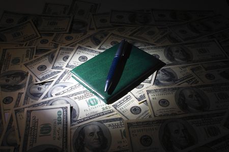 Notepad and pen on the money backgroundの写真素材