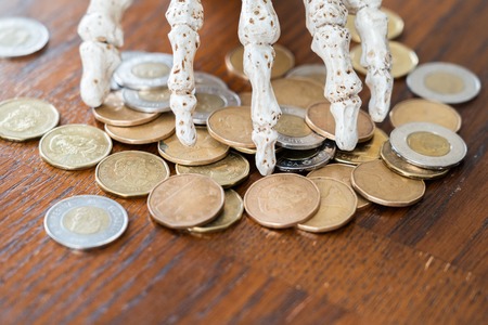 Skeleton hand guarding coins during halloweenの写真素材