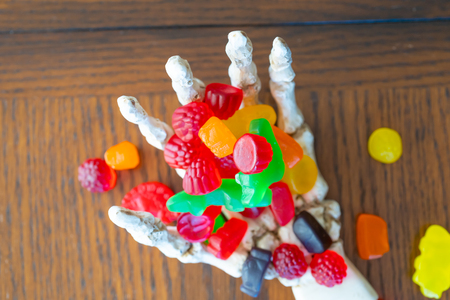 Skeleton hand offering bowl of Candy during halloweenの写真素材