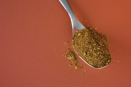 Spoonful of Dry Ground Peppers - Chili - on red backgroundの写真素材