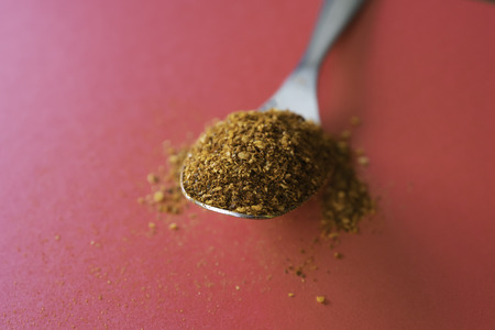Spoonful of Dry Ground Peppers - Chili - on red background