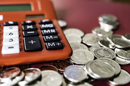 Red table top calculator with Silver coinsの写真素材