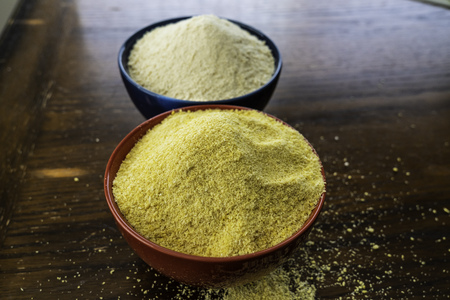 Two bowls of yellow and white Nigerian Garri on Tableの写真素材