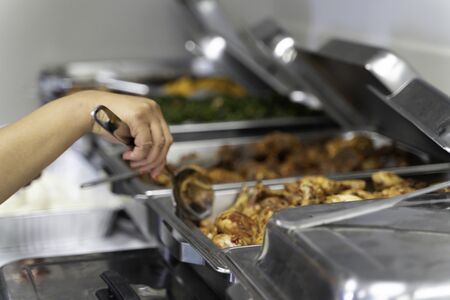Nigerian African American Woman filling chaffing Dish with food at Party