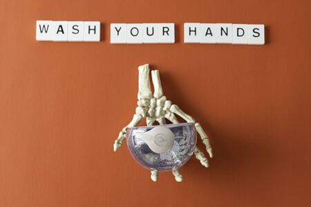 Wash your hands spelled with letter Tiles and a bottle of hand sanitizer