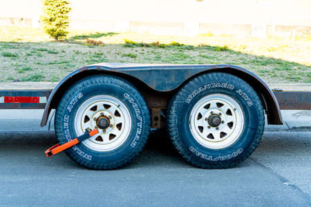June 30 2019 - Calgary , Alberta Canada - Clamped wheels on a trailer . Illegal parking on street