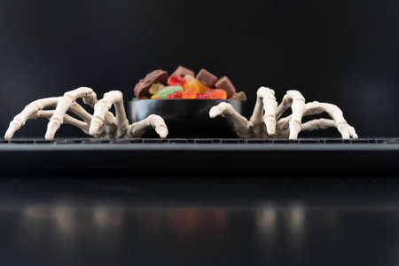 Skeleton hands on keyboard with bowl of Halloween candiesの写真素材
